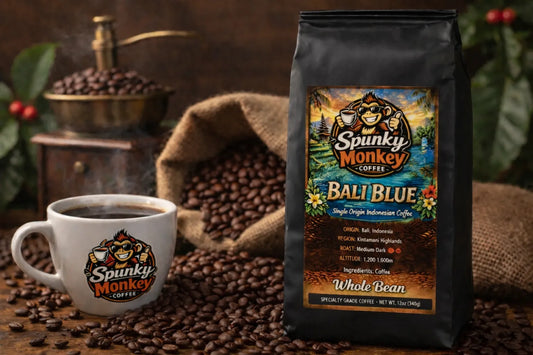 Spunky Monkey Coffee Bali Blue whole bean bag, steaming mug with logo, coffee grinder, beans.